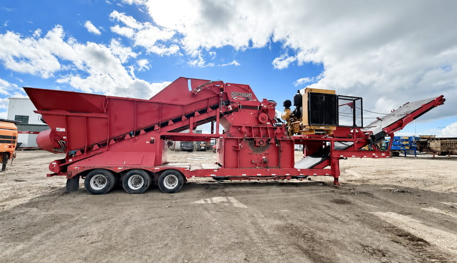 A red dump truck transporting a large construction machine on its flatbed.